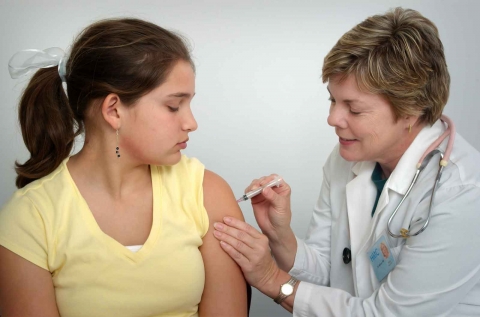 Teen girl receiving an injection in her upper arm